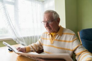 Un monsieur âgé qui lit un journal.